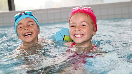 Een jongen en meisje lachend in het zwembad.